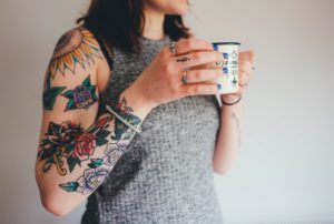 woman with tattoos drinking out of a mug - crushed vegan aftercare