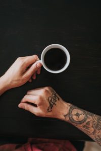 man with tattoos drinking coffee - crushed vegan aftercare